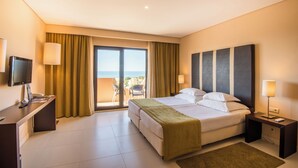 Ein Hotelzimmer mit Bett, Nachttischen, einem Schreibtisch mit Computer, einem Fernseher und einem Balkon mit Blick.