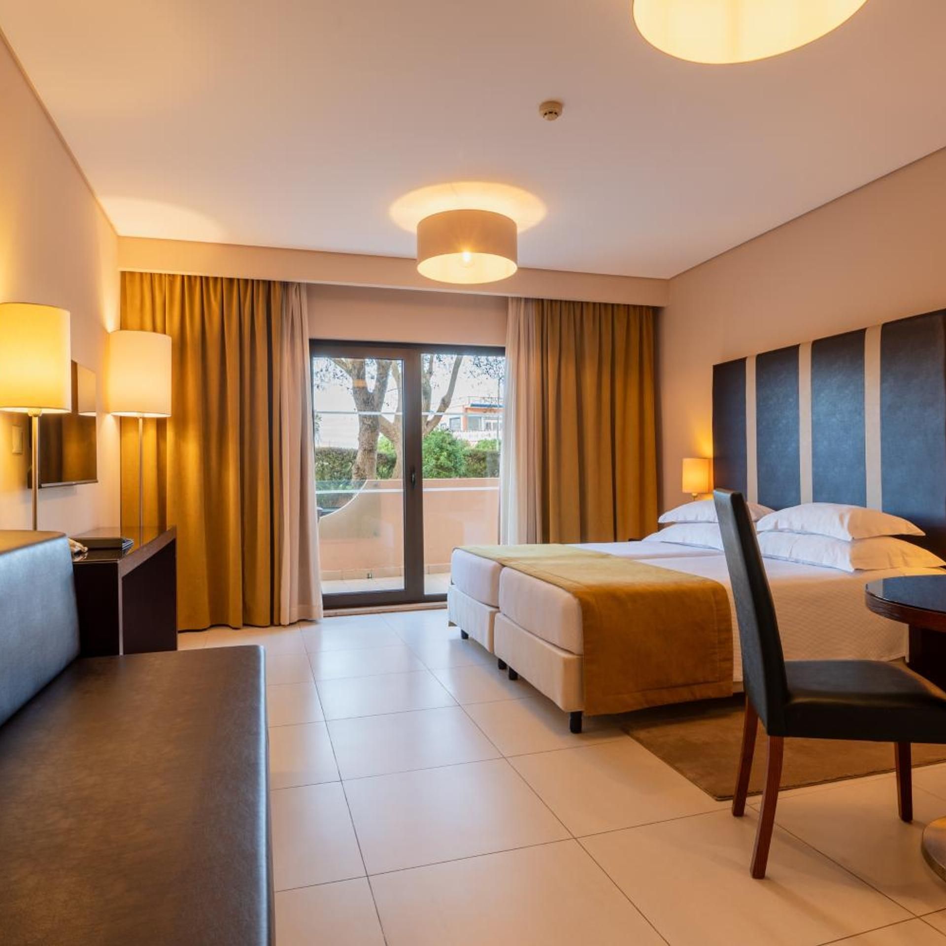 A hotel room with a bed, a desk, a chair, and a view of the outdoors.