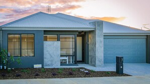 Ein modernes Einfamilienhaus mit Garage, einer Veranda und einem gepflegten Garten.