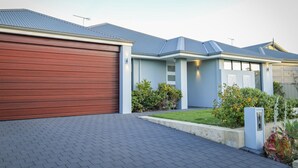 Een modern huis met twee verdiepingen, een garage, een verzorgd gazon en een oprit van baksteen.