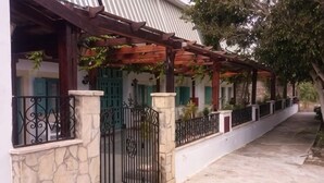 Un espace extérieur abrité, doté d’un mur en pierre, d’un portail en métal et d’une pergola couverte de plantes grimpantes.