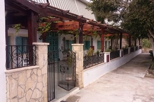 A covered outdoor area with a stone wall, metal gate, and a pergola with climbing plants.