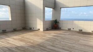 Ein geräumiges Zimmer mit Holzboden und großen Fenstern mit Meerblick.