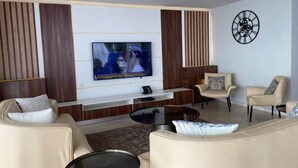 Ein modernes Wohnzimmer mit Flachbildfernseher, Ledersofas, einem Couchtisch und einer Wanduhr.