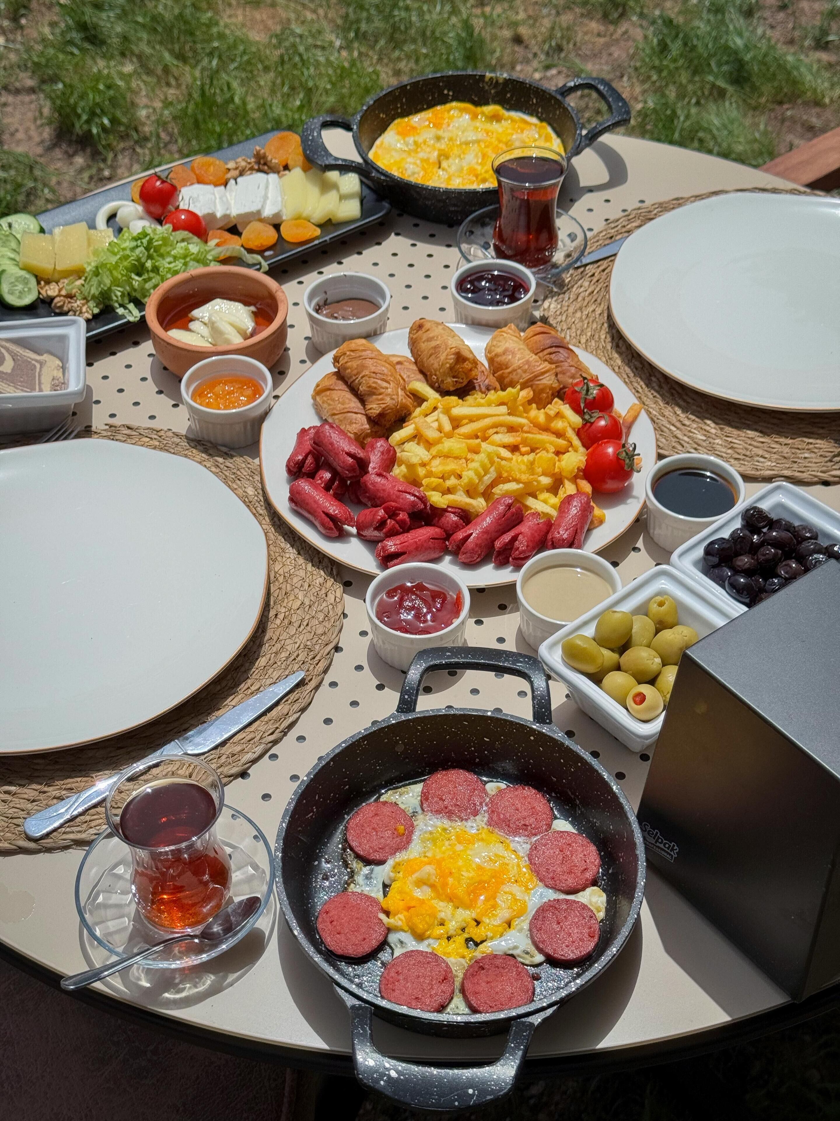 Una mesa dispuesta con diversos alimentos, incluyendo salchichas, huevos y verduras.