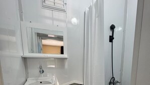 A compact bathroom with a sink, toilet, and shower. - ONES PANSİYON (Kumluca)