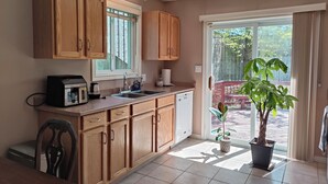 A kitchen with wooden cabinets, a built-in oven, and a sink. There is a potted plant and a sliding glass door leading to an outdoor area. - Perfect 3 bedroom house in prime location of South Windsor. max 5 guests (Windsor)