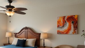 A bedroom with a bed, two bedside lamps, a ceiling fan, a chair, and a painting on the wall. - Perfect 3 bedroom house in prime location of South Windsor. max 5 guests (Windsor)