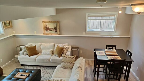 A living room with a sofa, ottoman, and dining table with chairs. - Perfect 3 bedroom house in prime location of South Windsor. max 5 guests (Windsor)