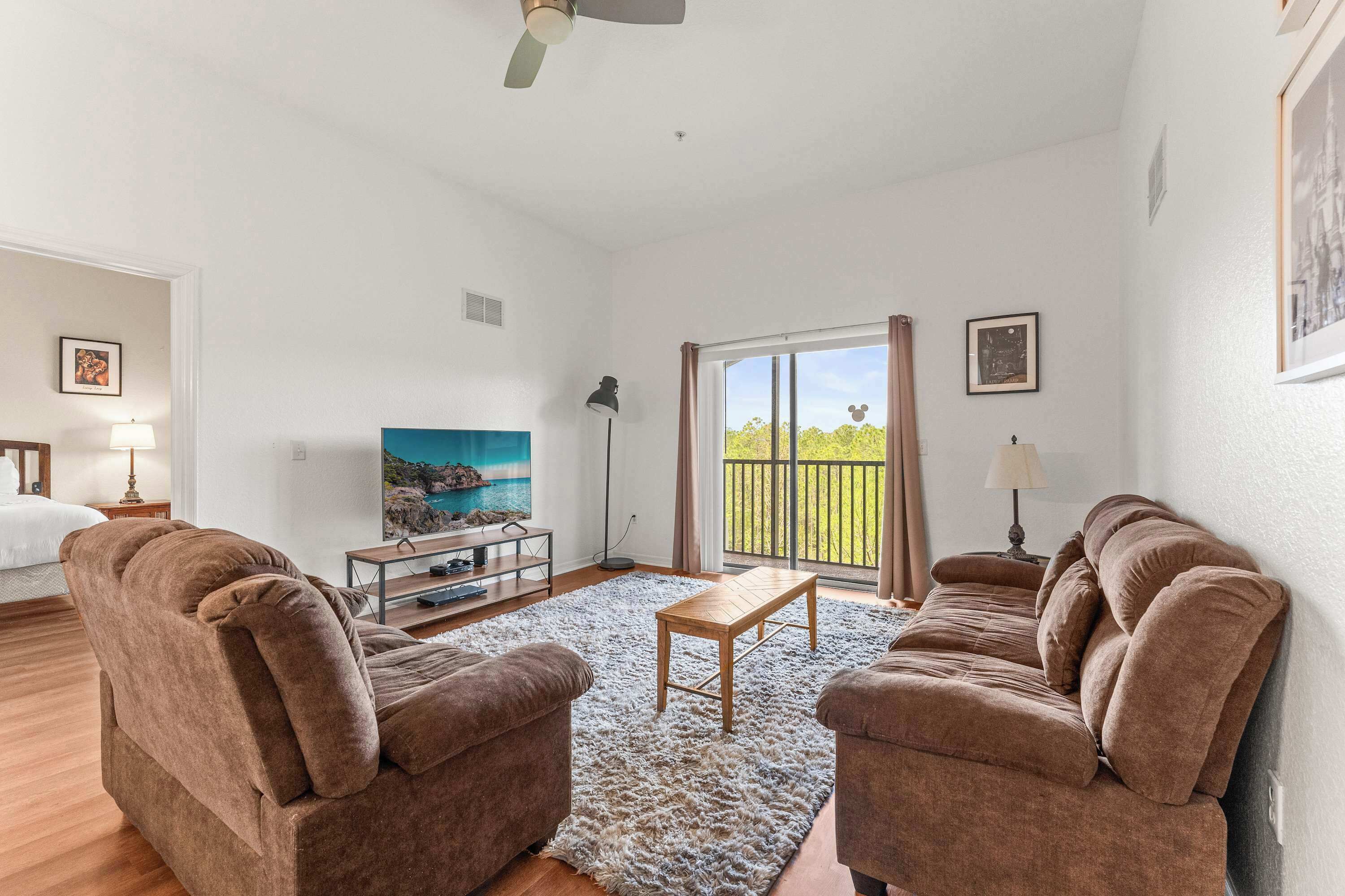 A spacious living room with two brown sofas, a wooden coffee table, and a large flat-screen TV.
