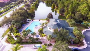 A residential area with a swimming pool, a house with a sloped roof, and a lake. - Bella Notte At Caribe Cove (Kissimmee)