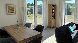 A room with a wooden dining table, chairs, a sofa, and a cabinet with shelves. - Vacation home Wiesenblick (Spangenberg)