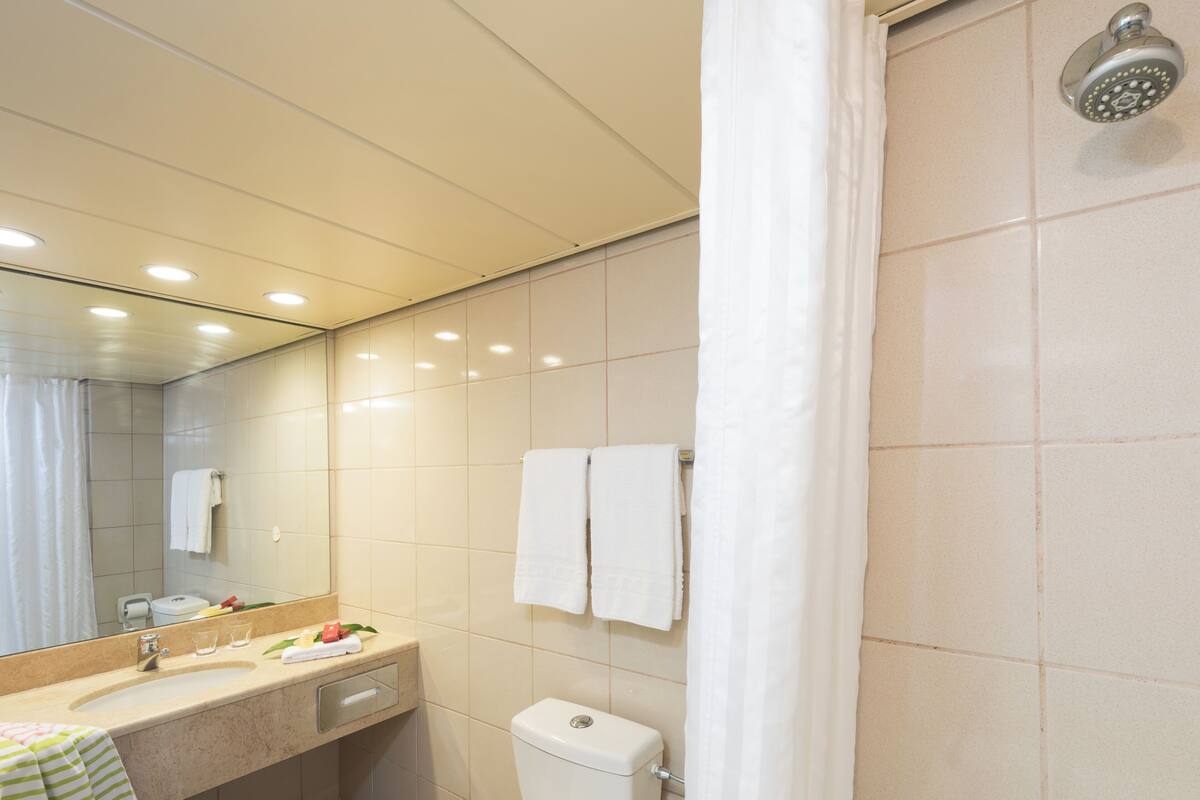 Une salle de bain moderne équipée d’un lavabo, d’un miroir, de toilettes et d’une douche.