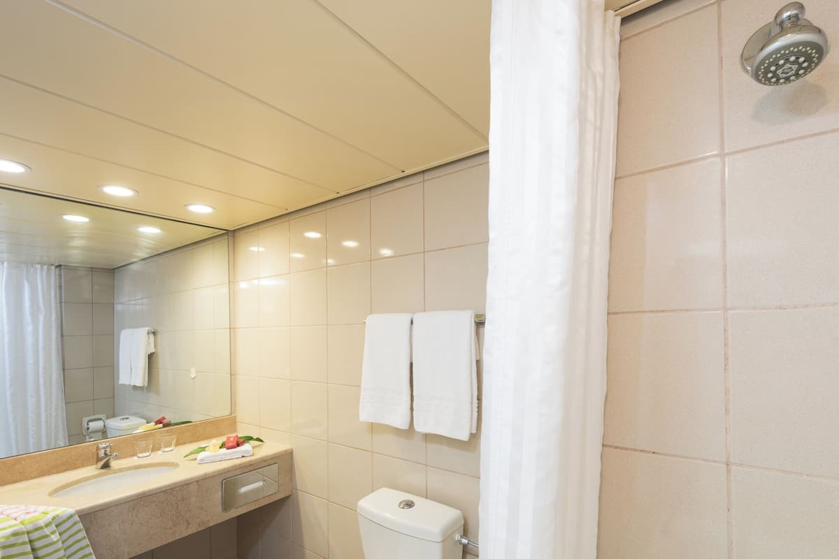 A modern bathroom with a sink, mirror, and toilet. There are two white towels hanging on the wall.