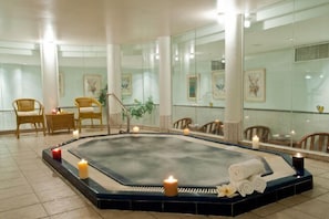 Unwind in a serene spa area with a central hot tub, wicker chairs, and elegant artwork.