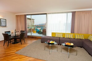 A living room with a sofa, two coffee tables, a dining table with chairs, and a view through a sliding glass door. - U Magic Palace (Eilat)