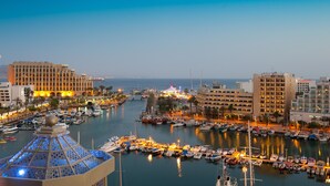 A marina with boats docked, a large hotel building, and a distinctive dome structure. - U Magic Palace (Eilat)