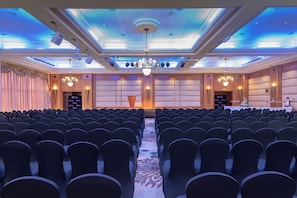 A conference room with rows of chairs, a stage with a podium, and a chandelier. - U Magic Palace (Eilat)
