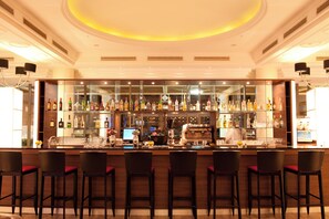 A bar area with multiple stools, a bar counter, and a variety of bottles and glasses. - U Magic Palace (Eilat)