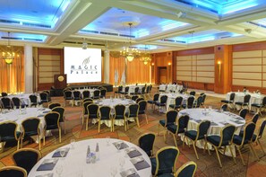 A banquet hall with round tables, chairs, and a large screen displaying 'MAGIC Palace.' - U Magic Palace (Eilat)