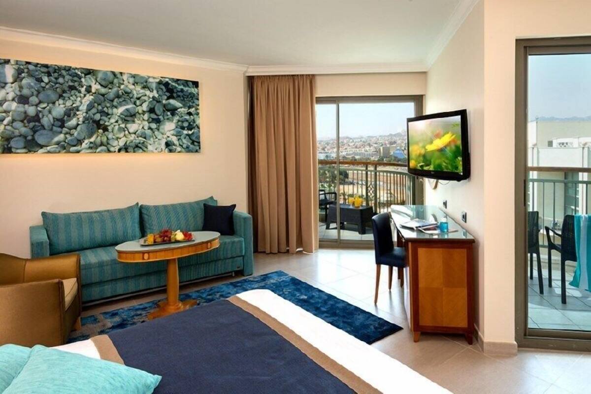 Une chambre d’hôtel comprenant un lit, un canapé, un bureau, une télévision et un balcon avec vue sur la ville.