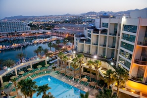Un hotel con piscina, varios pisos y vistas a la ciudad.