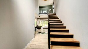 Un escalier moderne avec des marches en bois menant à un palier situé au deuxième étage.