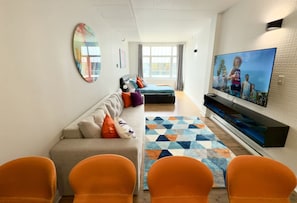 A modern living room with a sofa, chairs, a TV, and a patterned rug. - Urban Escape: Cozy, Modern & Well-Equipped Loft (Québec)