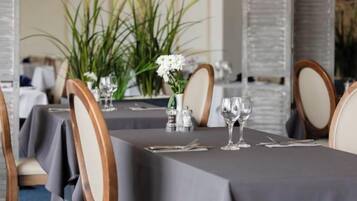 Una mesa de comedor con sillas, un florero con flores y un salero y pimentero.