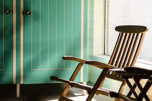 A wooden chair in a room with teal-colored walls and a window.