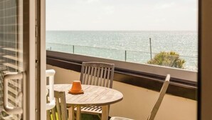 A balcony with a view of the sea, a round table with chairs, and a small orange object on the table. - Beachcroft Hotel, BW Signature Collection by Best Western (Felpham)