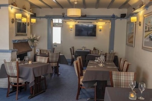 A restaurant with tables set for dining, chairs, and a television mounted on the wall.