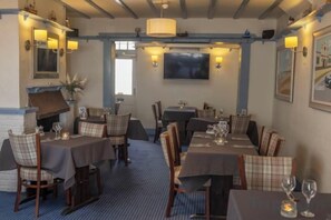 A restaurant with tables set for dining, chairs, and a television mounted on the wall. - Beachcroft Hotel, BW Signature Collection by Best Western (Felpham)