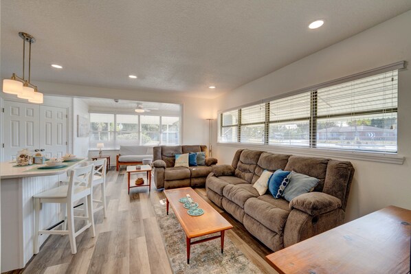 A spacious living area with a sofa, coffee table, and a kitchen area with a bar. - Break of Dawne (Kissimmee)