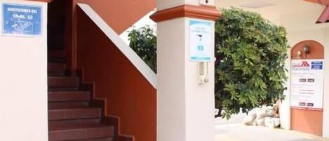 Un escalier menant à l’entrée d’un bâtiment, avec un panneau indiquant un espace de stationnement.