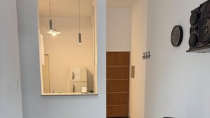 Ein moderner Essbereich mit einem runden Tisch, schwarzen Stühlen und einer schwarzen Tischdecke. Links ist eine Heizung und im Hintergrund eine Holztür zu sehen.