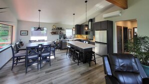 Una cocina moderna con una isla central, muebles oscuros e iluminación colgante.
