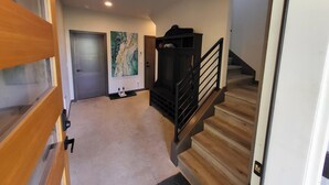 Un pasillo con una puerta de madera, una escalera y una pared con un cuadro.