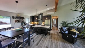 Una cocina moderna con armarios oscuros, una isla central e iluminación colgante.