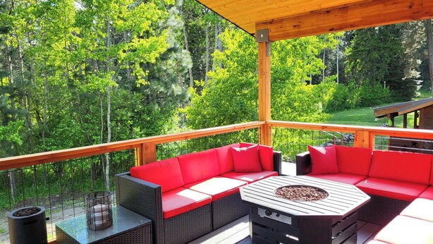 Una terraza techada con un sofá rojo, una mesa y una parrilla.
