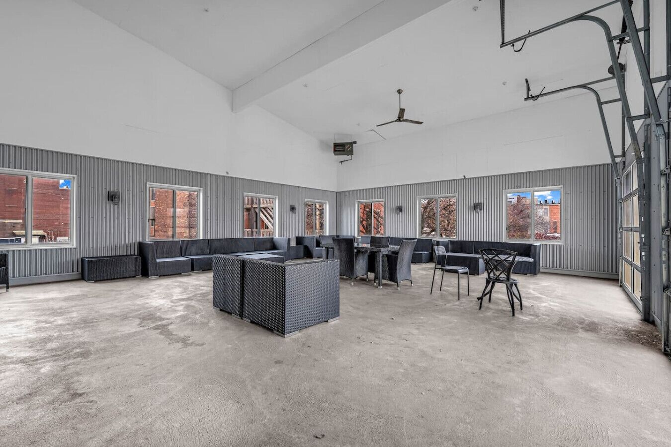 A spacious indoor area with high ceilings, large windows, and a concrete floor.