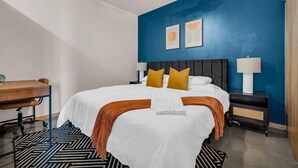 Une chambre d’hôtel avec un grand lit, deux tables de chevet, un bureau et un ventilateur de plafond.