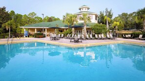 Une piscine avec des chaises longues et, au fond, un bâtiment doté d’un toit végétalisé.