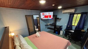 A hotel room with a bed, a desk, a chair, a television, and a window with curtains. - Pura Vida Aparment - Downtown La Fortuna (La Fortuna)