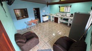 A compact living space with a kitchenette, a dining area with a table and chairs, and two sofas. - Pura Vida Aparment - Downtown La Fortuna (La Fortuna)