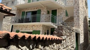 A two-story stone building with green shutters and a balcony. - Apartments Stone House Murter (Murter-Kornati)