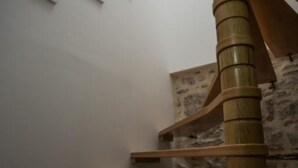 A wooden spiral staircase with a stone wall background. - Apartments Stone House Murter (Murter-Kornati)