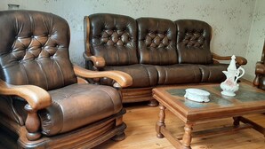 Un salon traditionnel avec un canapé en cuir marron, des fauteuils en bois et une table basse en bois agrémentée d’objets décoratifs.
