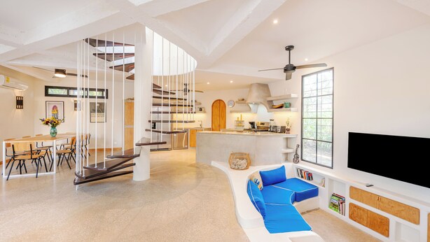 A spacious living area with a staircase, a kitchen, and a seating area with a TV.