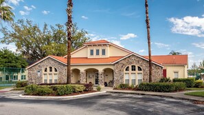 A two-story building with a stone facade, red-tiled roof, and arched windows. - Celebrate at Club Cortile (Kissimmee)